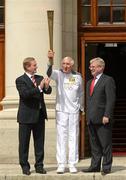 6 June 2012; Gold Medalist in the 1956 Olympic Games, Ronnie Delany, holds up the Olympic Flame alongside An Taoiseach Enda Kenny T.D., left, and Tánaiste Eamon Gilmore, T.D., right, outside Government Buildings during the London 2012 Olympic Torch Relay through the streets of Dublin. Merrion Square, Dublin. Picture credit: Barry Cregg / SPORTSFILE