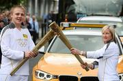 6 June 2012; Torchbearer Lee Kinsella hands over to Olivia O'Toole, from Sheriff Street, Dublin, who has won over 130 caps with Ireland’s women international soccer team and was the Irish captain. Olivia has scored more goals for Ireland than Robbie Keane – a record 54. She is employed at Sheriff Street Recreation Centre as a Play & Recreation worker for Dublin City Council and also trains the Sheriff St. Youth Club football team – continuing the strong soccer tradition in the Inner City, during the London 2012 Olympic Torch Relay through the streets of Dublin. Mayor Street, Dublin. Picture credit: Ray McManus / SPORTSFILE