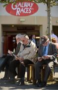 30 July 2012; A general view of racegoers checking the form before the day's racing. Galway Racing Festival 2012, Ballybrit, Galway. Picture credit: Barry Cregg / SPORTSFILE