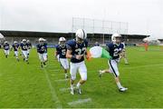 31 August 2012; The Kent School team led by Jason Kozel, left, and Connor Mitchell, carry an Irish tricolour as they run onto the pitch before the game. Global Ireland Football Tournament 2012, Kent School, Connecticut, v National School of American Football, Ireland/UK, Parnell Park, Dublin. Picture credit: Brendan Moran / SPORTSFILE