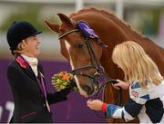 4 September 2012; Silver medalist in the Ind. Freestyle Test - Grade III event, Deborah Criddle, Great Britain, laughs as her mount  LJT Akilles takes a bite of her flowers. London 2012 Paralympic Games, Equestrian, Greenwich Park, Greenwich, London, England. Picture credit: Brian Lawless / SPORTSFILE