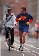 25 October 1999. American Eric Black &quot;Superman&quot; is followed by a cycling cameraman during the 98FM 1999 Dublin City Marathon. Athletics. Picture credit; Brendan Moran/SPORTSFILE